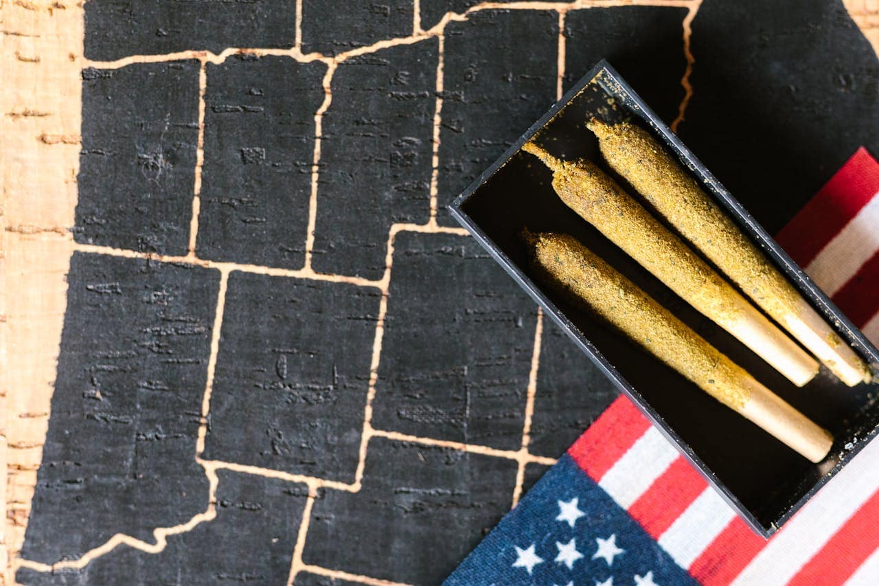 Close-up of cannabis joints on a rustic map with an American flag. Ideal for discussing marijuana culture.